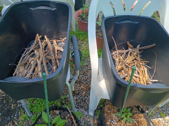 Two storage totes. the bottoms are filled with branches and twigs